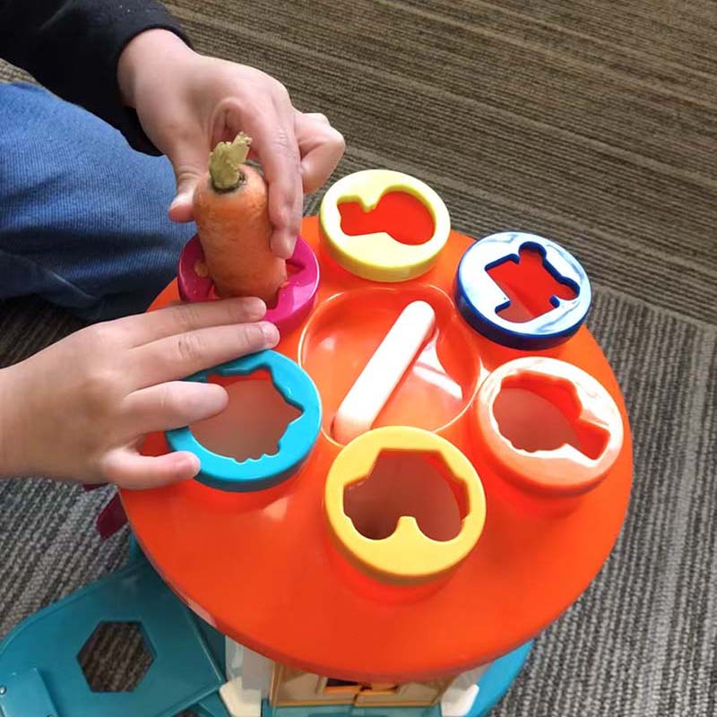 Child playing a carrot into a shape-sorting game